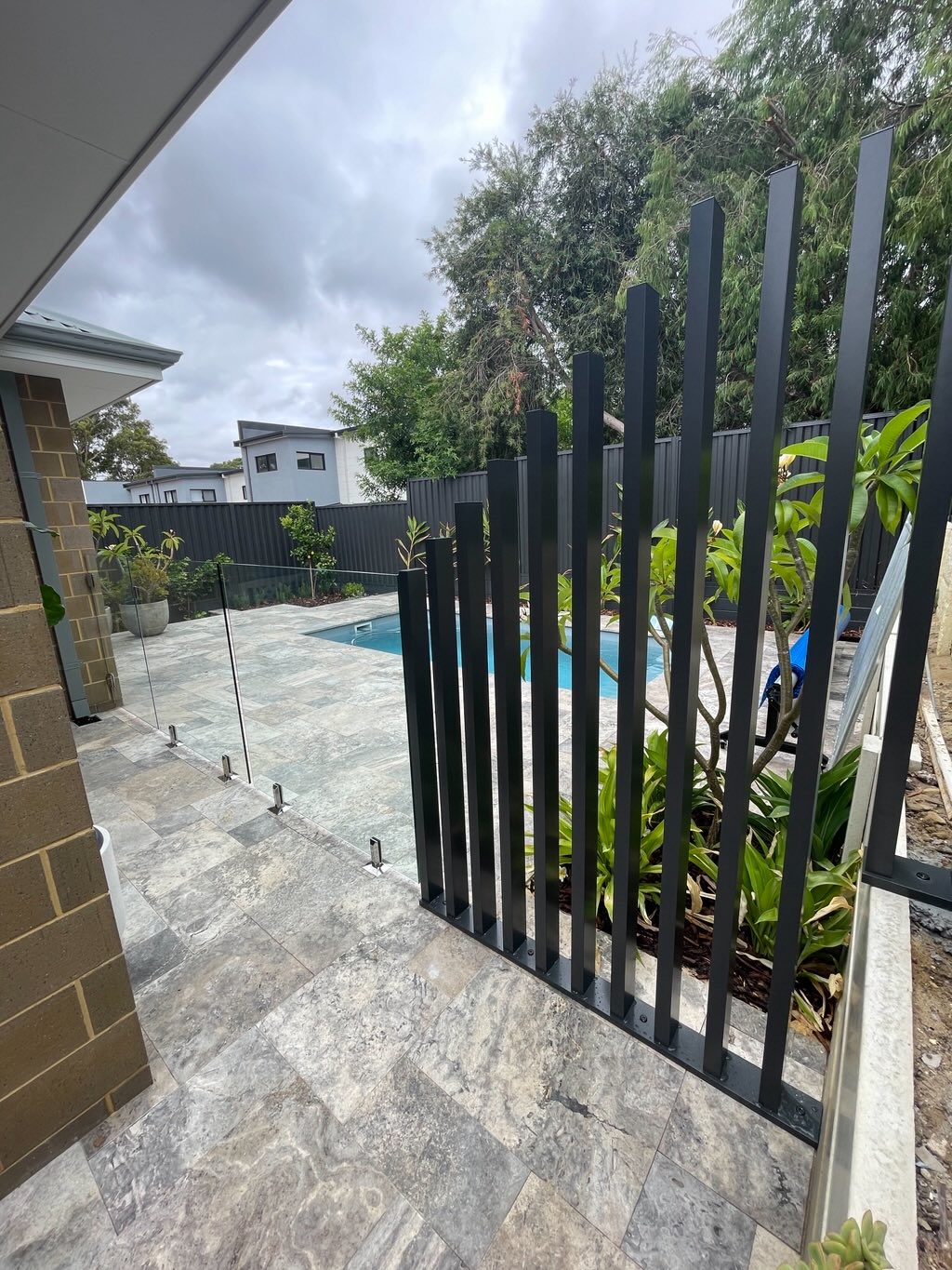 Dark batten fence next to glass pool fencing